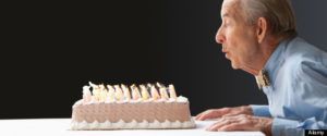 Senior Hispanic man blowing out birthday candles