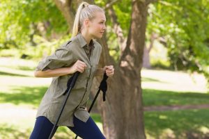 Beautiful young woman Nordic walking in park