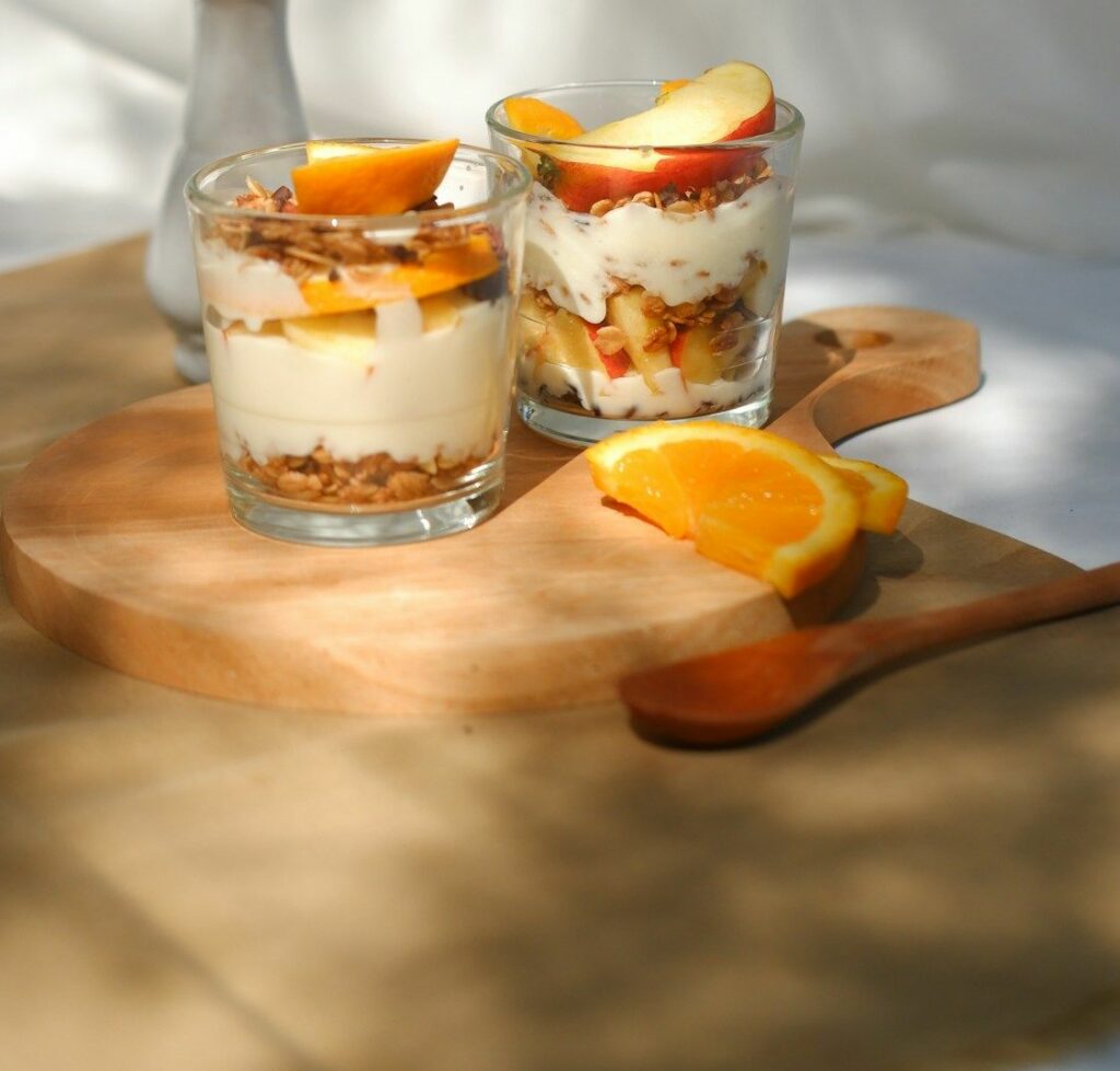 due bicchieri con crema, muesli e frutta