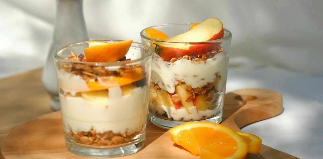 due bicchieri con crema, muesli e frutta