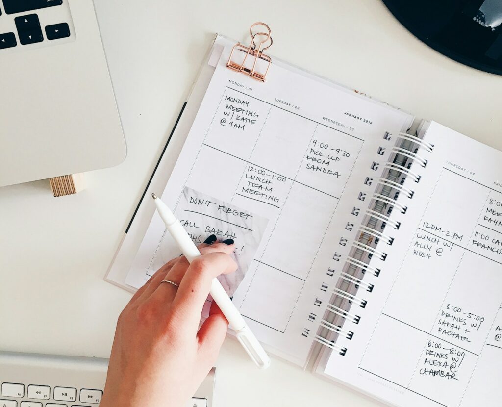 persona che scrive su agenda per programmare la giornata.