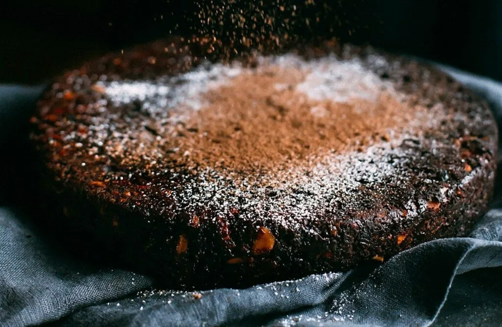 torta al cioccolato foto persona che spolverizza di cacao una torta